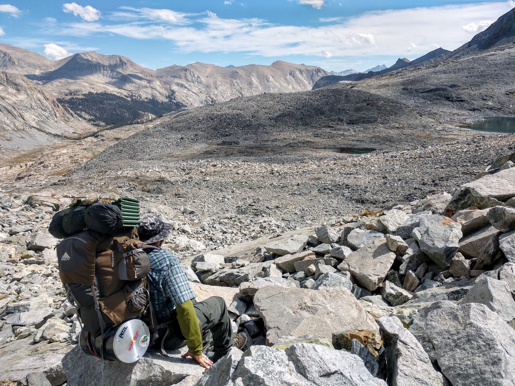 Photo taken from behind Kyle sitting looking out at a barren rock field off-trail in the Sequoia back country